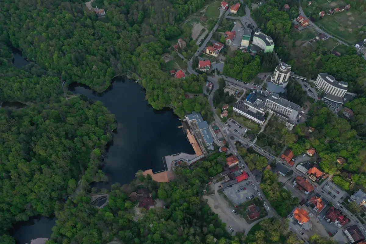 Lacul Ursu din Sovata văzut de sus, vara, înconjurat de pădure, cu hotelurile stațiunii pe mal
